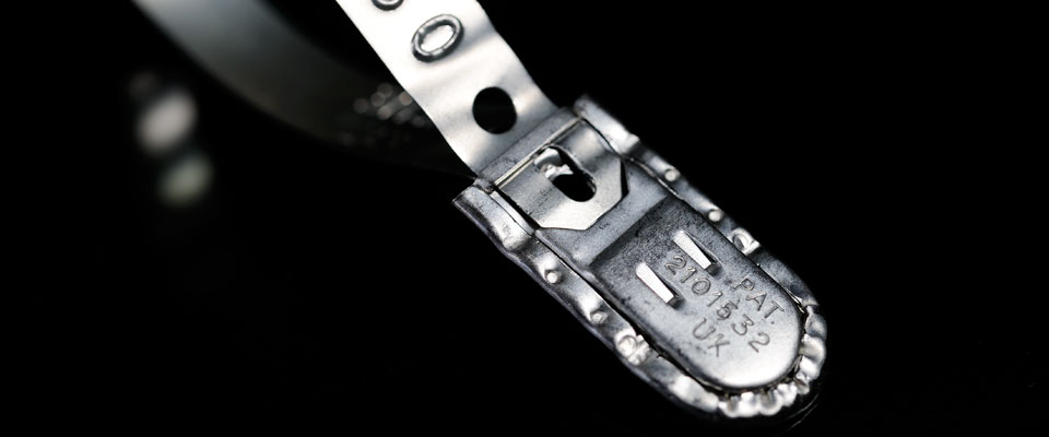 The patented locking mechanism features inspection holes to confirm positive locking while crimped and folded edges show evidence of physical intrusion into the locking box.